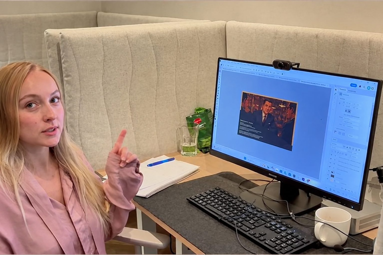 An intern at her desk in the studio, explaining a design on screen